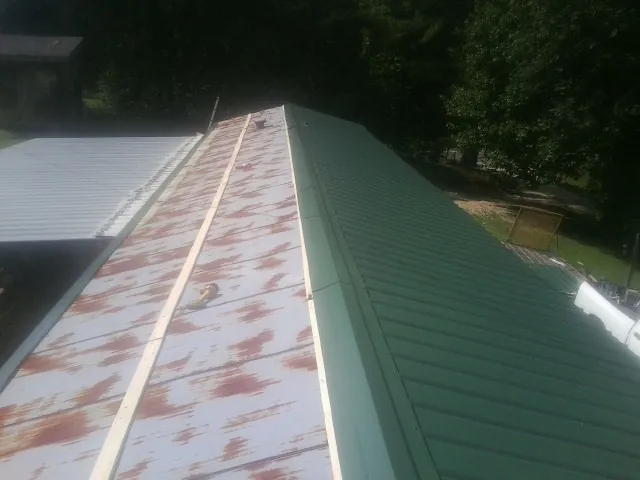 Old rusted panels beside newly installed green metal roofing — Wind Damage Roof Repair by Roofing Brothers in Lombard