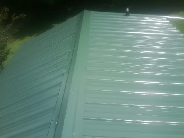New green metal panels meeting at the ridge of a roof — Flat Roof Repair work by our crew in Lombard