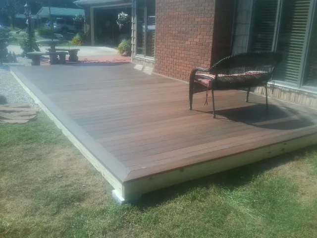 New wood deck and wicker chair beside a brick house in Lombard