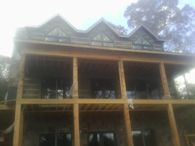 Dormers and porch framing on a large log home under construction — Roof Coating work by our crew in Lombard