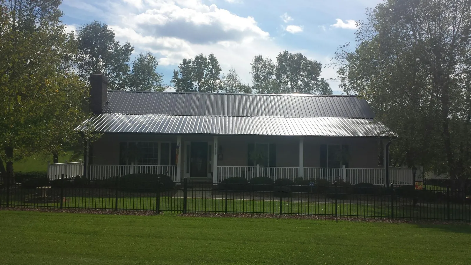 Gray metal roof on a brick ranch with a full width front porch — Gutter Guard Installation work by our crew in Lombard