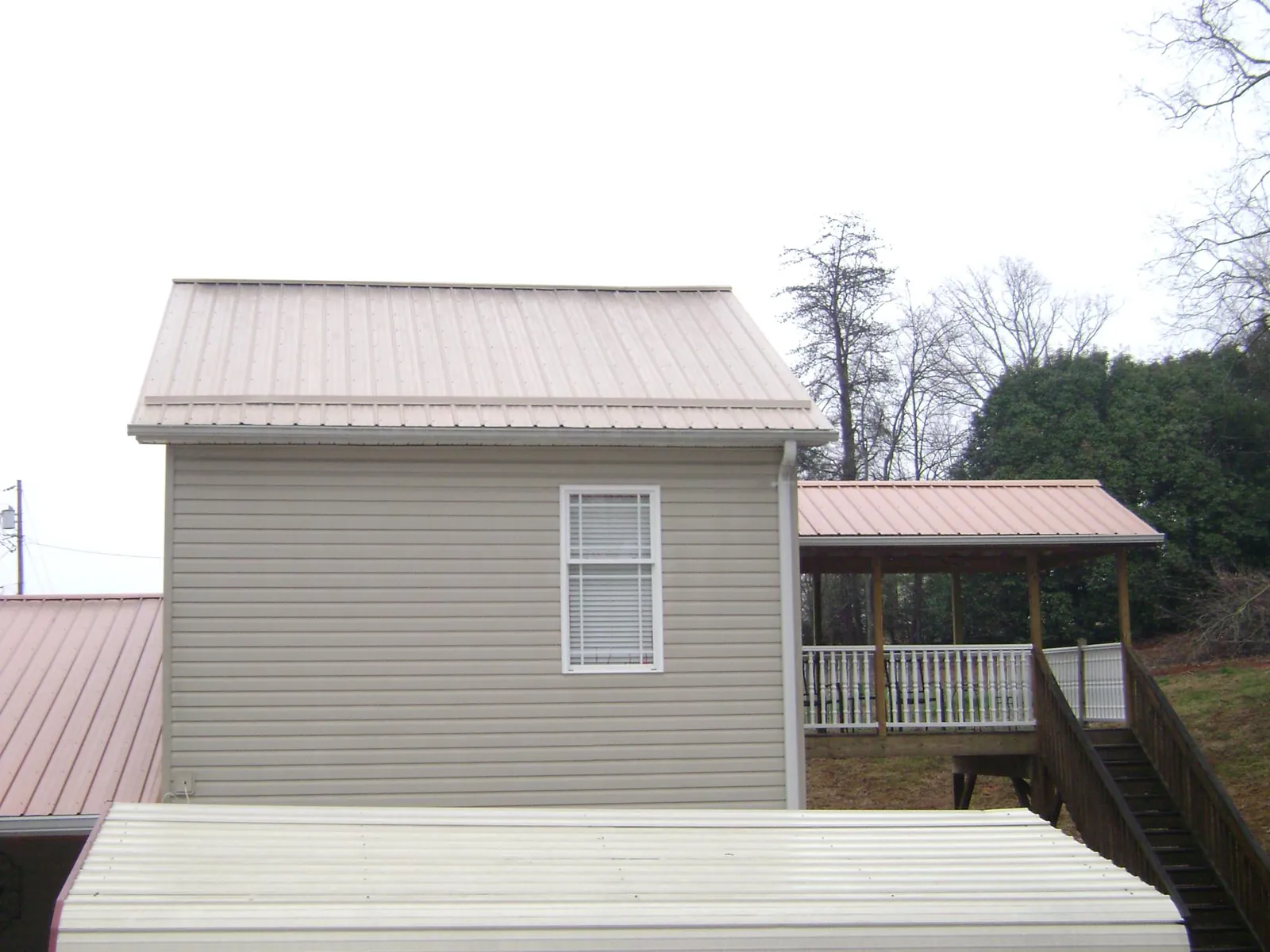 Tan metal roofs on a two story addition and attached porch, from a Roof Replacement job in Lombard