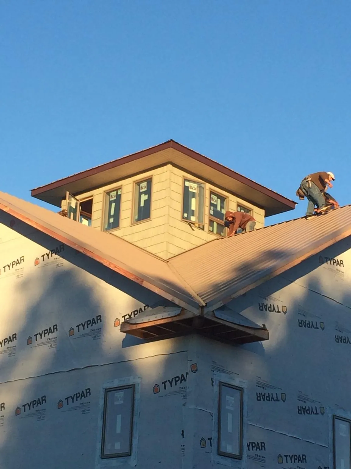 Roofers working around a rooftop cupola on a new metal roof at sunset — Roof Waterproofing in Lombard by Roofing Brothers